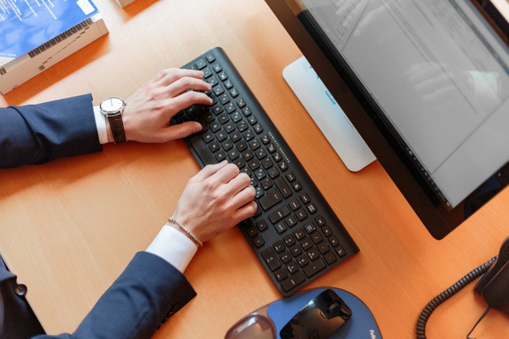 personne en costume qui tape sur un ordinateur de bureau